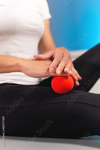 Close-up of a male massage therapist showing a client how to use and massage a ball. Myofascial thigh massage