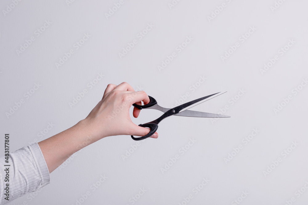 Stationery scissors in the hand of a girl on a white background Stationery scissors in the hand of a girl on a white background