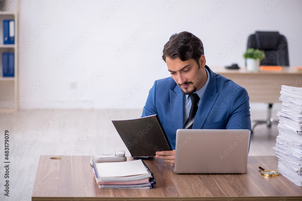 Young male employee unhappy with excessive work in the office Young male employee unhappy with excessive work in the office