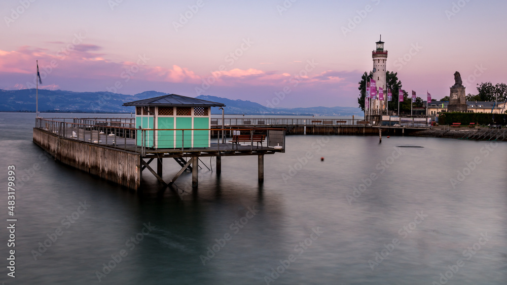 Green bathhouse on a jetty in Lake Constance. In the background the lighthouse from the island of Lindau