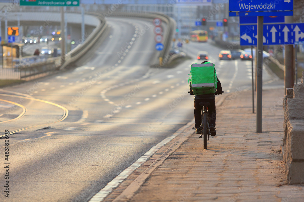 Kurier jedzie na rowerze we Wrocławiu, dostarcza jedzenie.  - obrazy, fototapety, plakaty 