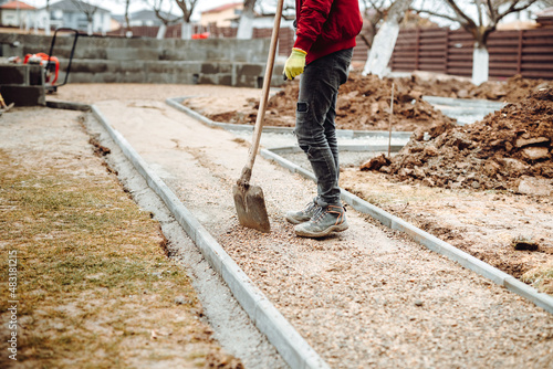 Worker using pavement slabs and shovel to build stone sidewalk. Close up of construction worker installing and laying pavement stones on terrace, road or sidewalk. © aboutmomentsimages