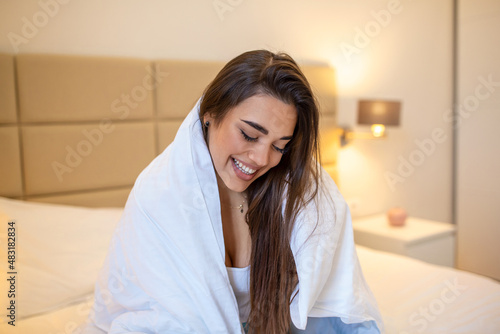 Express tenderness. Cute young woman keeping smile on her face while looking away wrapped at the white blanket. Stock photo
