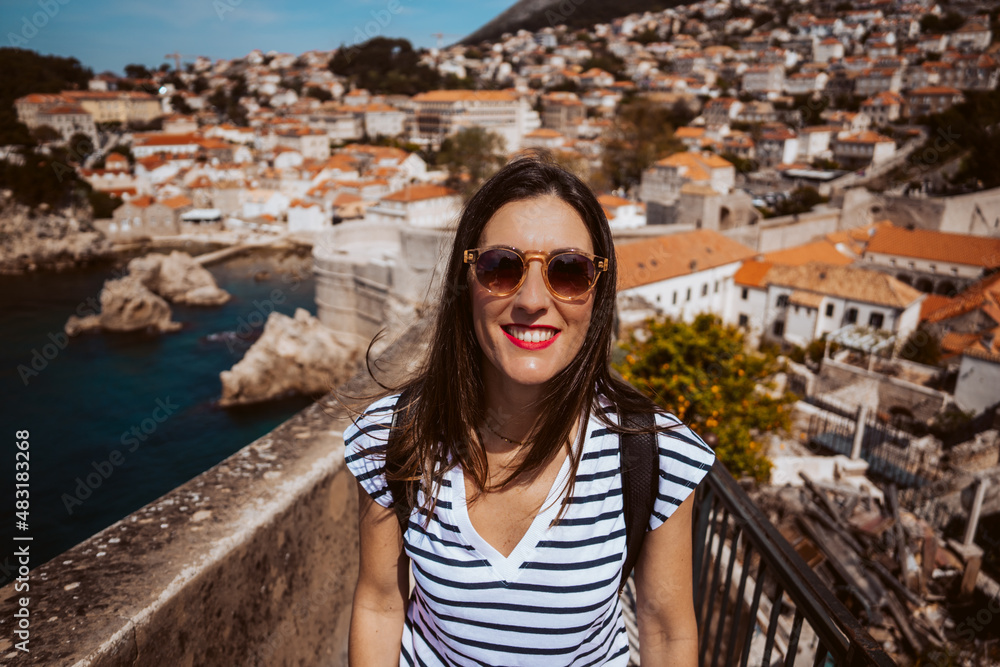 Laughing young woman tourist walking on the city walls of dubrovnik in croatia. Travel photography