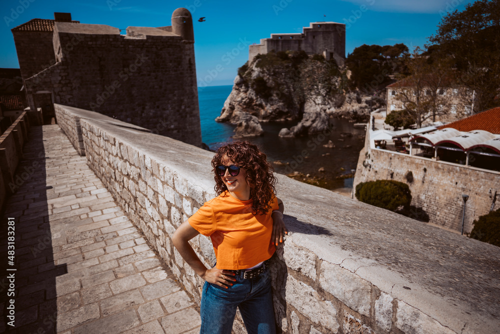 Laughing young woman tourist walking on the city walls of dubrovnik in croatia