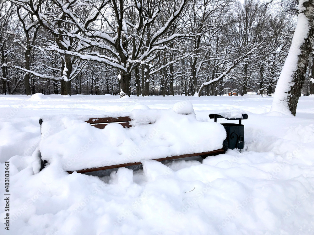 Bench in the park covered with snow. Snowy winter