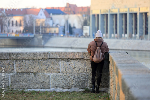 Kobieta stoi nad rzeką Odrą we Wrocławiu.