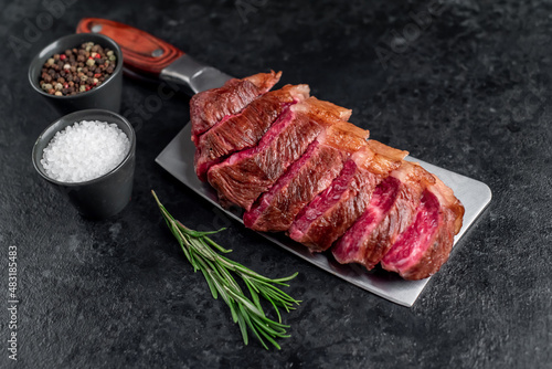 grilled picanha steak with spices on a meat knife on a stone background