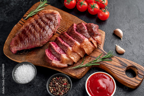 Two grilled picanha steaks with spices on a stone background 