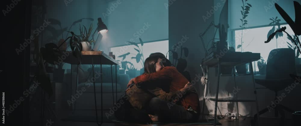 A man and woman sit on the floor of apartment hugging A man and woman sit on the floor of apartment hugging