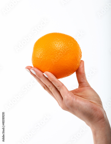 Woman hand holds fresh orange over white
