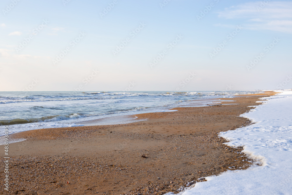 Sea winter landscape. Sea strip and coastal sand line with snow