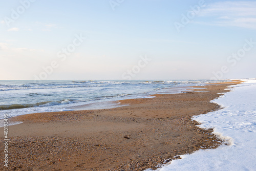 Sea winter landscape. Sea strip and coastal sand line with snow