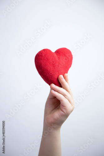 Child hand holding a red heart, white background. healthy life and love concept 