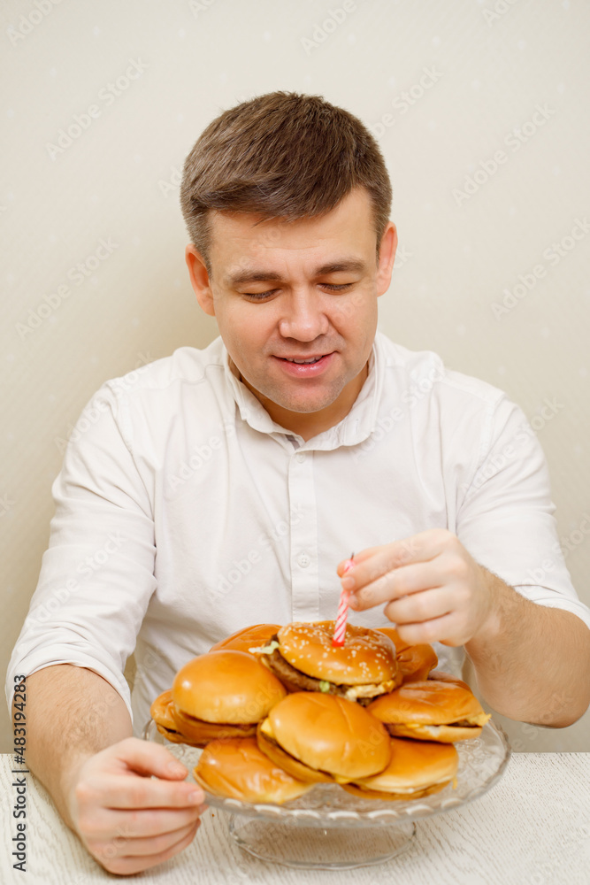 happy man makes wish and blows out candle on hamburger cake. cake for men. happy man makes wish and blows out candle on hamburger cake. cake for men.