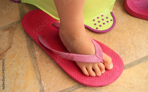 Foot of a child in a pink flip flop sandal of an adult