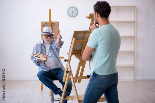 Old painter and young male model at the studio