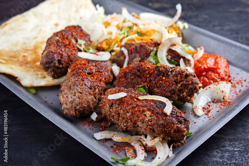 Traditional Croatian cevapi spicy meat ball rolls with cabbage carrot salad, pita bread and hot ajvar sauce served as close-up in a metal tray