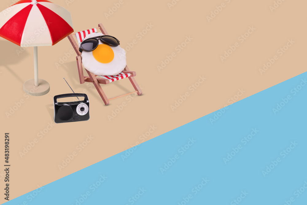 Creative funny composition made of sun umbrella, radio, fried egg with sunglasses sitting on deck chair on the beach.