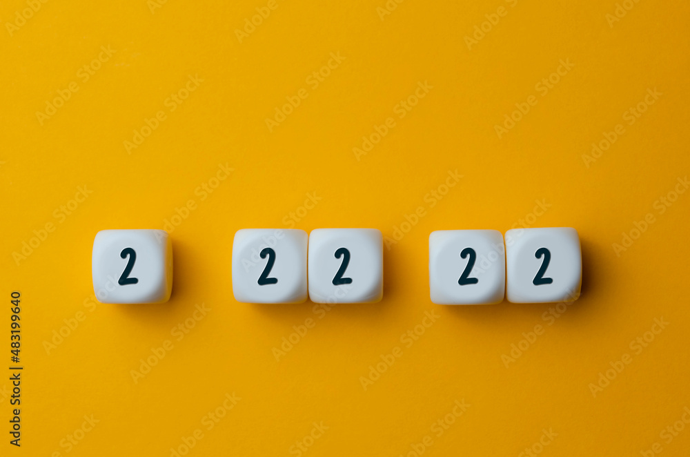 The unique date is February 22, 2022. Numbers 2 22 22 on white cubes shapes on yellow background. The unique date is February 22, 2022. Numbers 2 22 22 on white cubes shapes on yellow background.