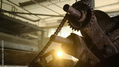 Old rusty gears with chain in abandoned vintage factory. Light enters through holes in cogwheel. Slow close up footage in old vintage not working plant.