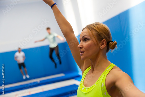 Closeup portrait of emotional young athletic woman exercising acrobatic jump elements in trampoline center .. © JackF