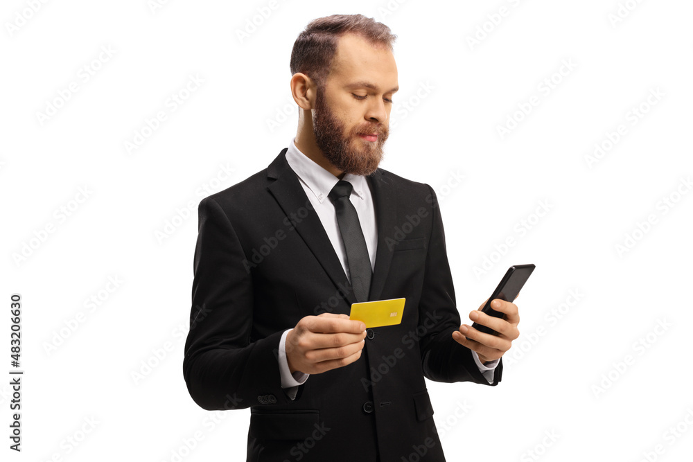 Businessman holding a credit card and looking at a mobile phone Businessman holding a credit card and looking at a mobile phone