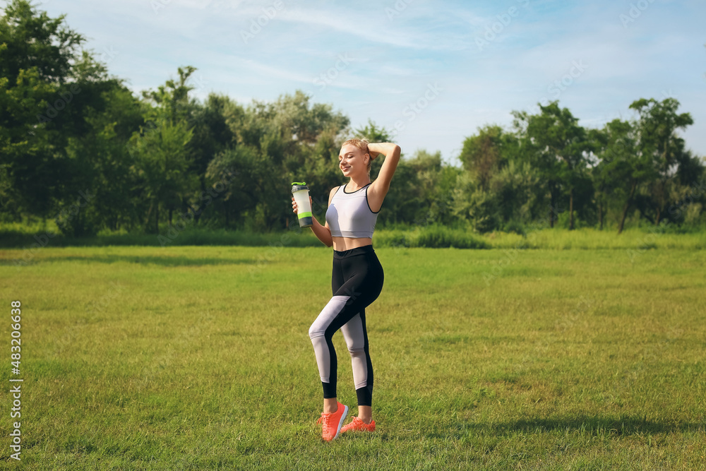 Young woman in sportswear holding bottle of protein shake outdoors Young woman in sportswear holding bottle of protein shake outdoors