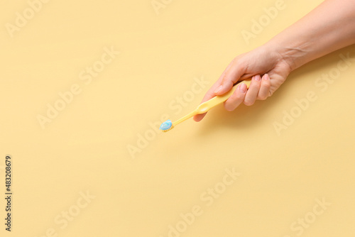 Female hand with tooth brush and paste on beige background