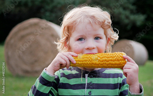 Obraz na płótnie Young cute caucasian 4-year old child with curly blonde middle-long hair eats co