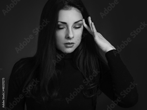 Business concentrate thinking woman find the answer in clever mind with closed eyes with fingers near the face in black sweater on dark shadow red background. Closeup front