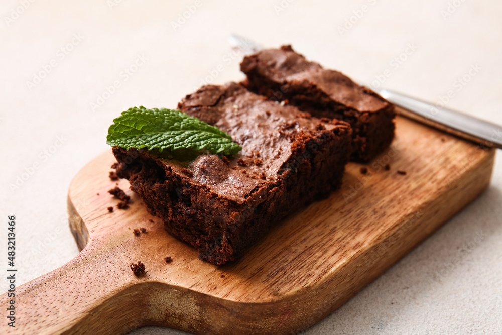 Wooden board with pieces of tasty chocolate brownie on white background