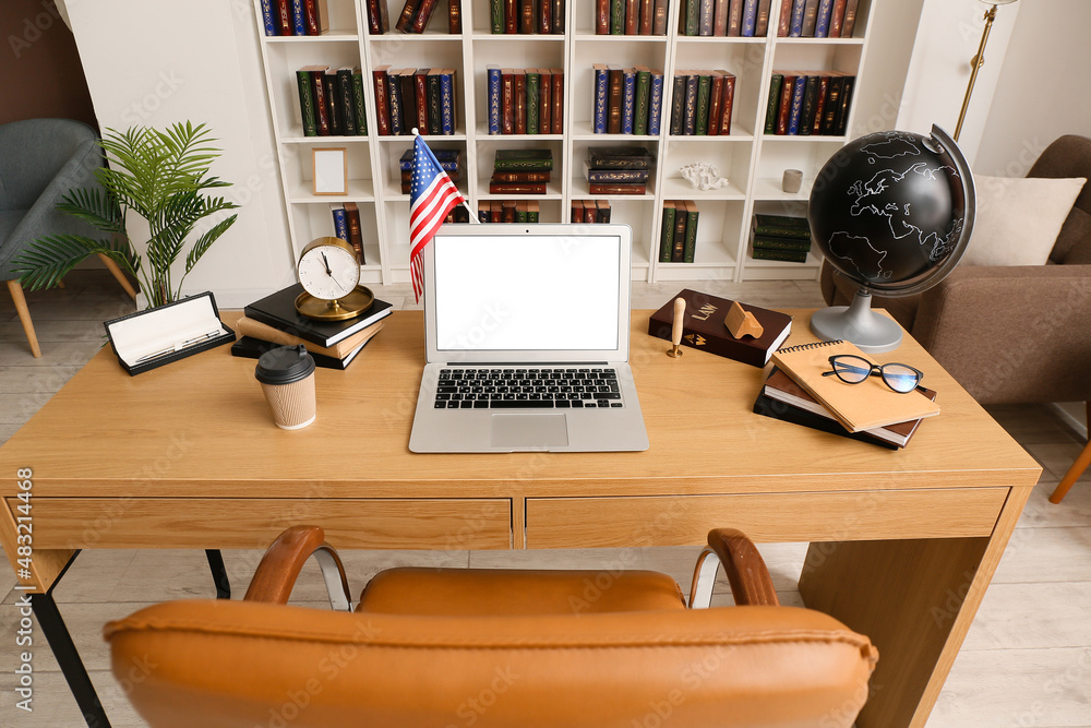 Fototapeta premium Laptop with blank screen and USA flag on desk in office