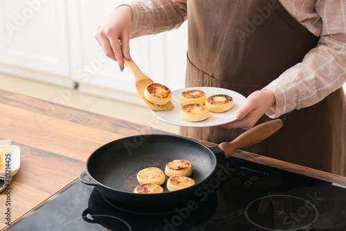 Woman preparing tasty cottage cheese pancakes in kitchen, closeup