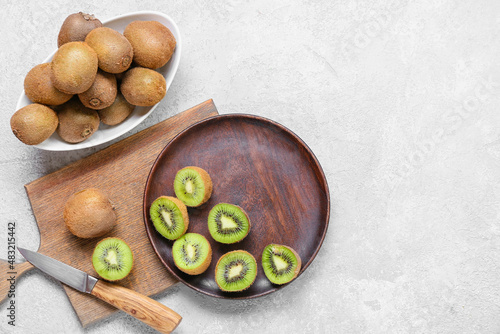 Plate with fresh cut kiwi on light background