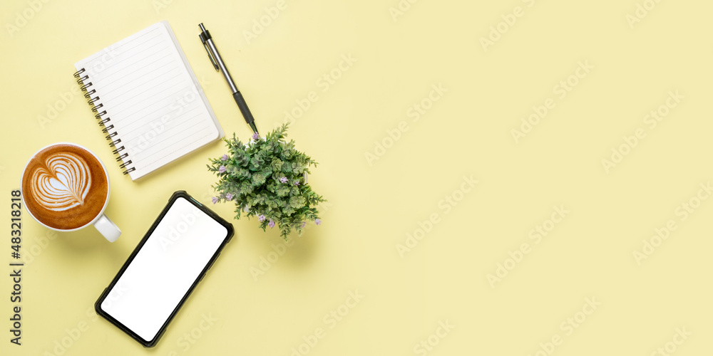 Office desk with Blank screen smart phone, Pen, Notebook, Cup of coffee on yellow background, Top view with copy space, Mock up.. Office desk with Blank screen smart phone, Pen, Notebook, Cup of coffee on yellow background, Top view with copy space, Mock up..