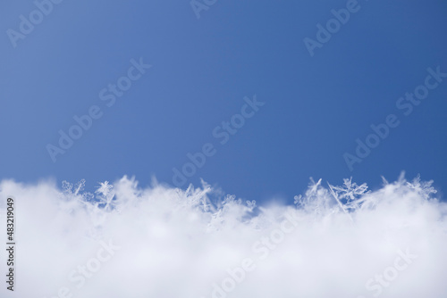 The surface of real crystal spiky snowflakes on a blue background with space for text. Christmas winter snow background macro with copy space.