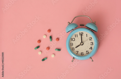 alarm clock on blue table with medication