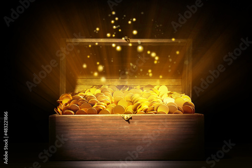 Open treasure chest with gold coins on table against black background photo