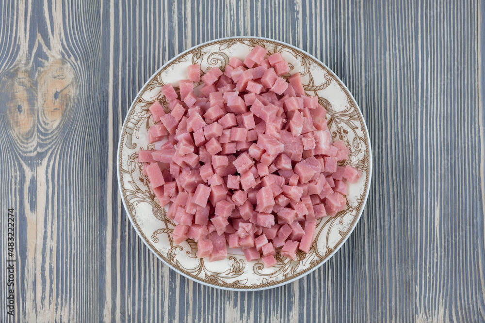 Sausage cut into small cubes in a wooden plate. Sausage cut into small cubes in a wooden plate.