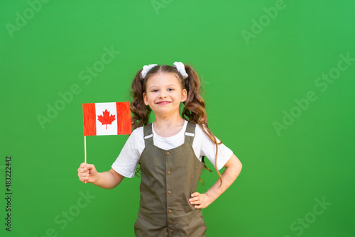 The flag of Canada in the hands of a child. A patriot girl receives a school education in her country.