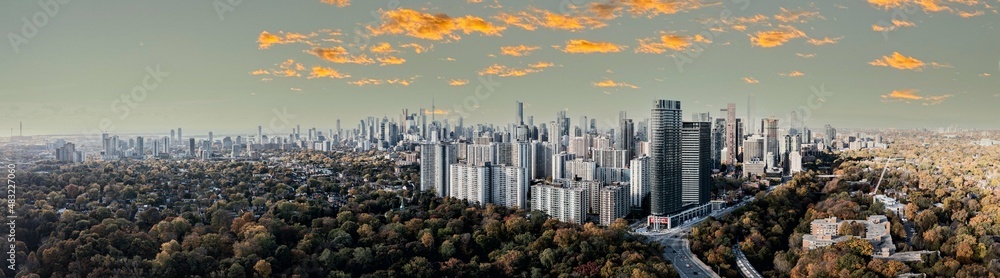 Fototapeta premium Drone Panorama of Toronto skyline with trees surrounding the cityscape sun set time 