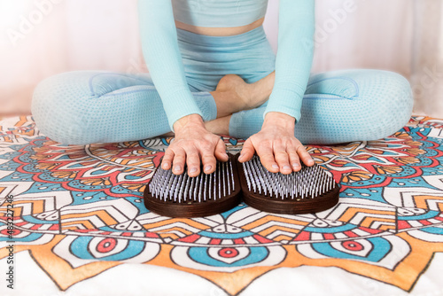 hobnail therapy on the Sadhu board. a girl in a blue suit holds her hands on nails on a sahu board Yoga practice. photo