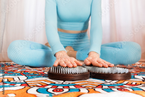 hobnail therapy on the Sadhu board. a girl in a blue suit holds her hands on nails on a sahu board Yoga practice. photo