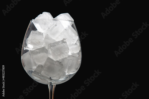 frozen ice cubes in an empty wine glass on a dark background