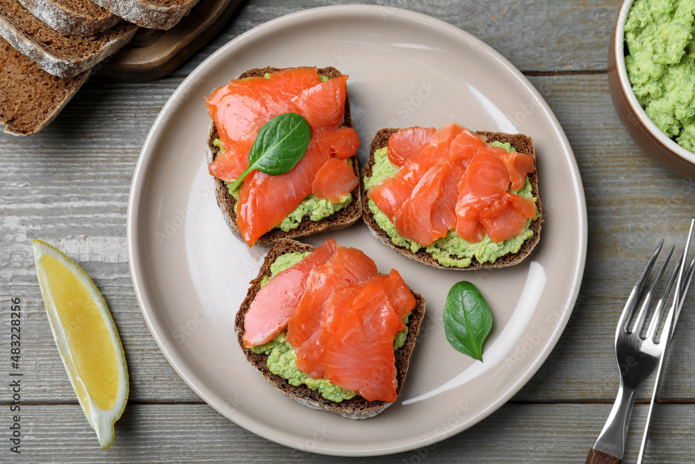 Delicious sandwiches with salmon and avocado served on grey wooden table, flat lay Delicious sandwiches with salmon and avocado served on grey wooden table, flat lay