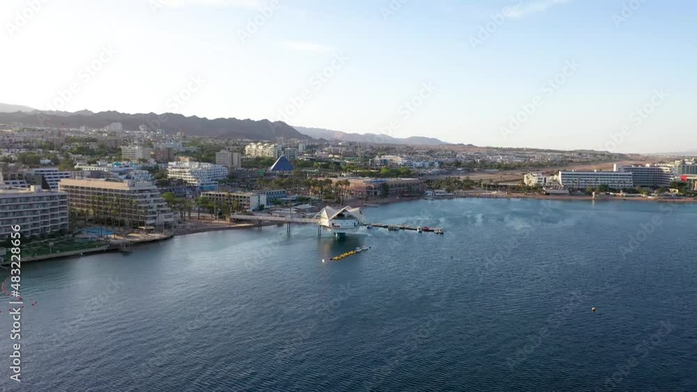 Touristic city of Eilat with multiple high hotels and apartments with in the underwater restaurant builded into the Gulf of Eilat. Drone panning shot Touristic city of Eilat with multiple high hotels and apartments with in the underwater restaurant builded into the Gulf of Eilat. Drone panning shot