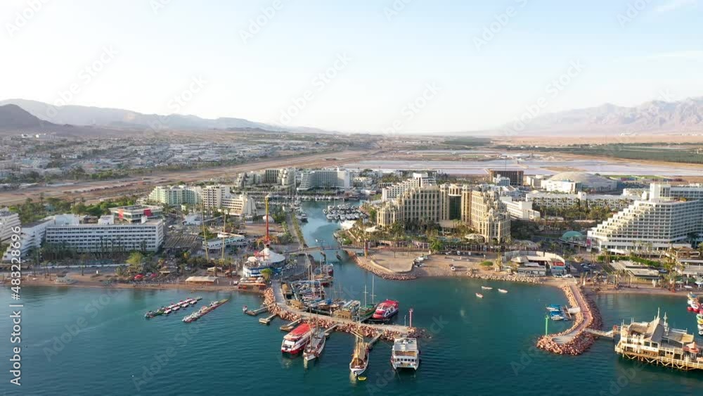 Multiple big hotels and resorts at the boulevard of Eilat with a mountain view and sea view on a bright sunny day. Drone panning shot Multiple big hotels and resorts at the boulevard of Eilat with a mountain view and sea view on a bright sunny day. Drone panning shot