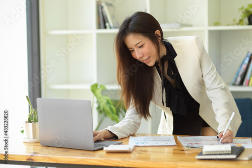 Businesswoman leaning on table and searching an informations on laptop. © bongkarn