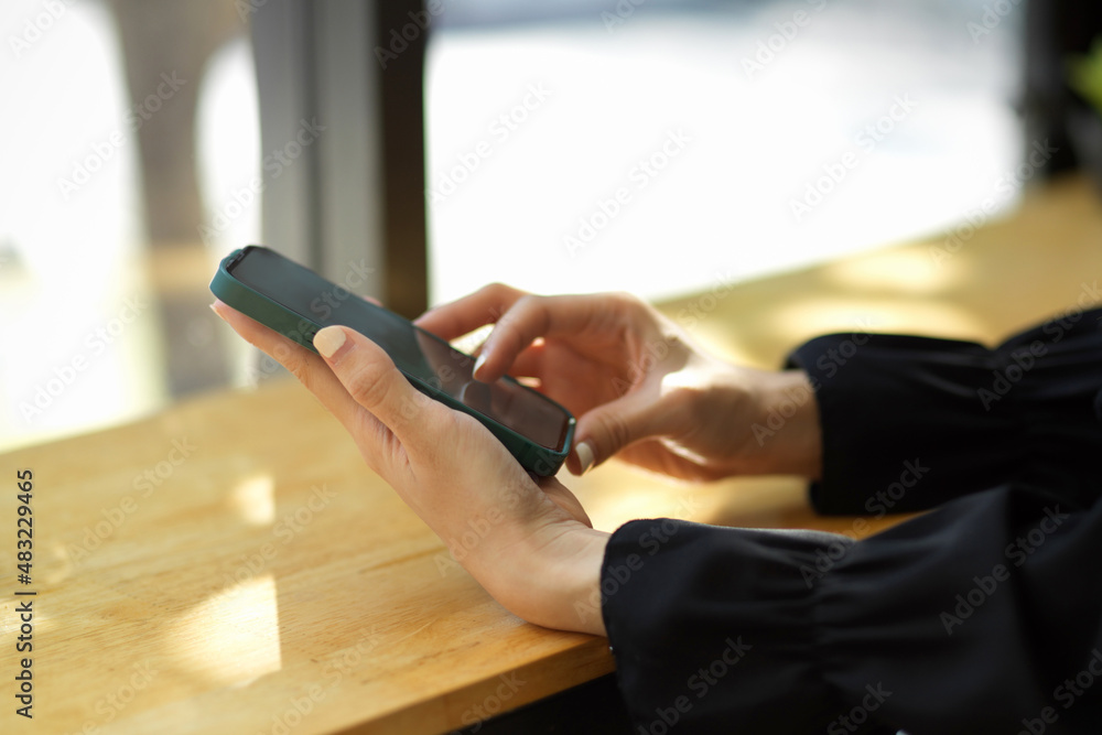 Close-up image of a female in black sweater typing on smartphone